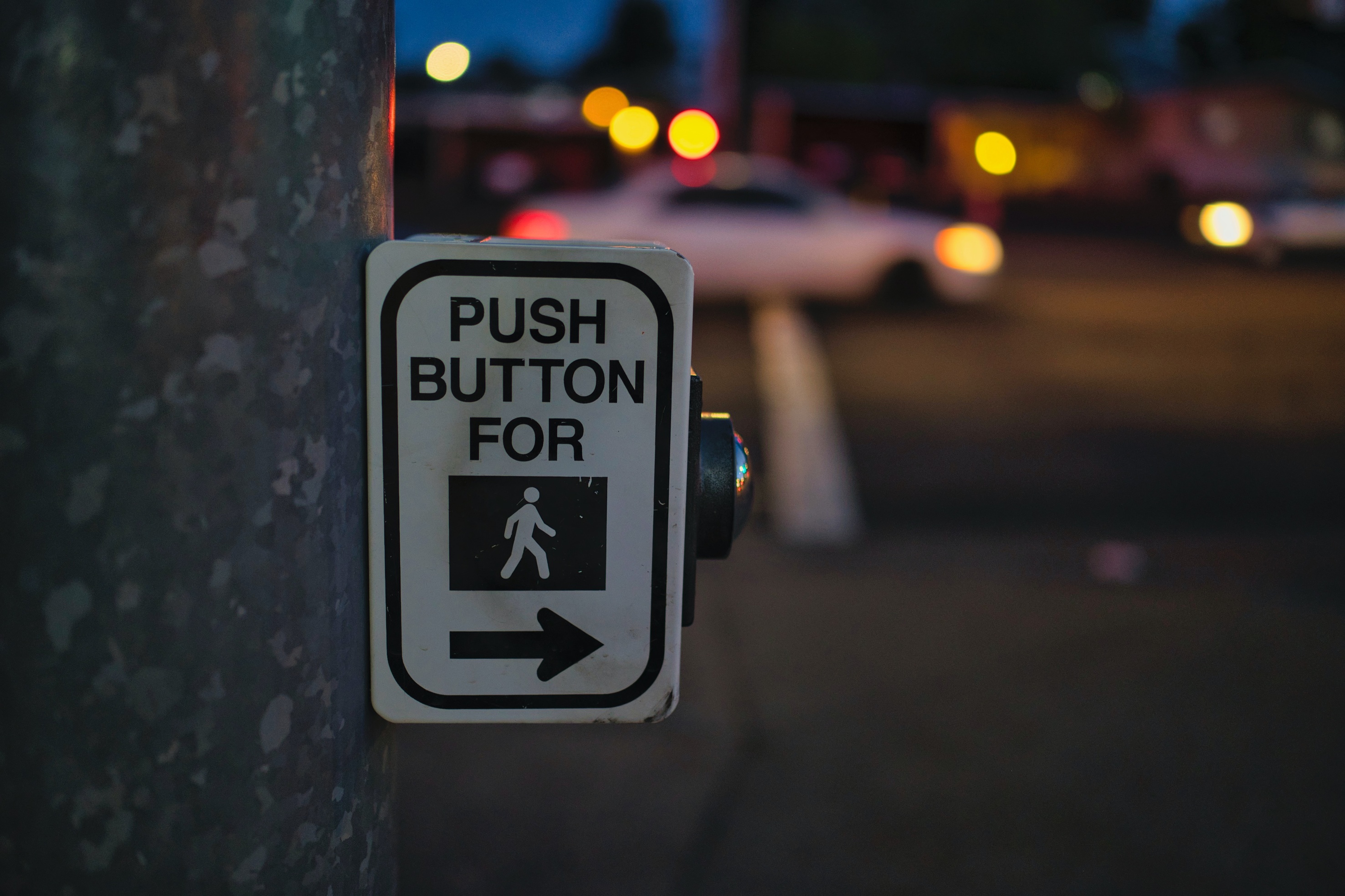 Cross walk button on side of a pole with universal image for a pedestrian.