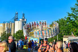 A carnival ride with grain siloes in the background