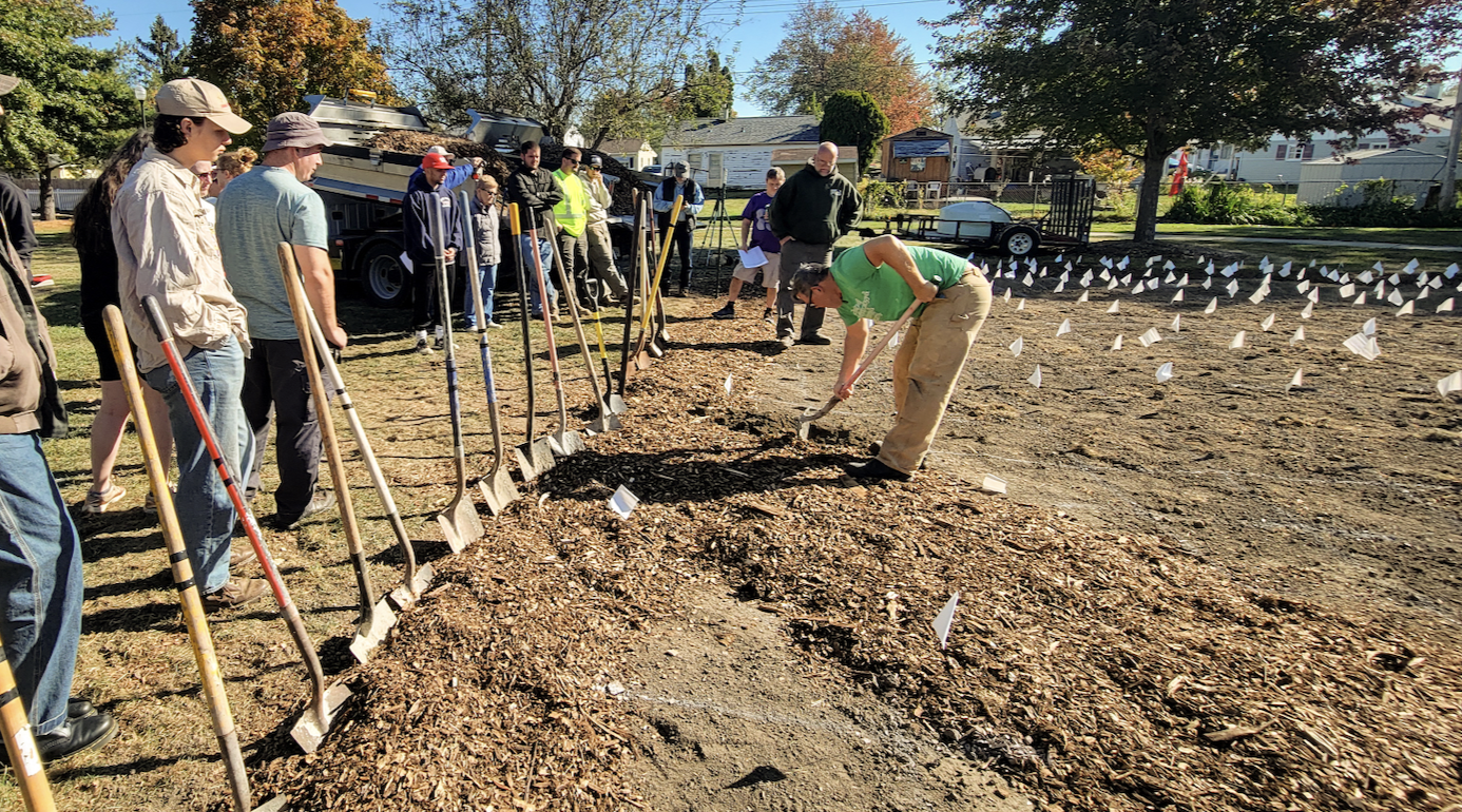 row of young people with shovels and freshly tilled dirt