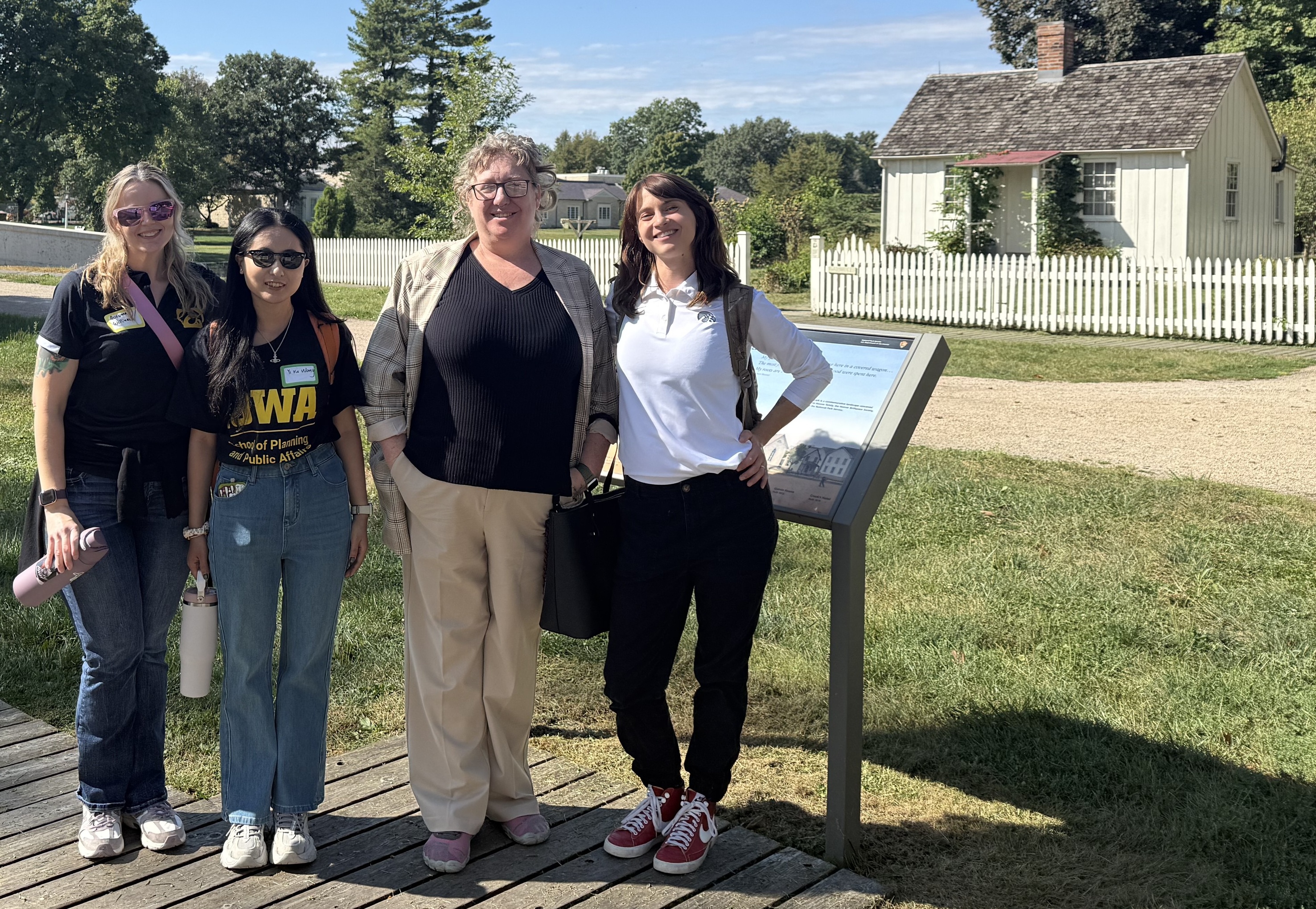 A group of 4 women stand in front of a the small white house that is Hoover's birthplace.