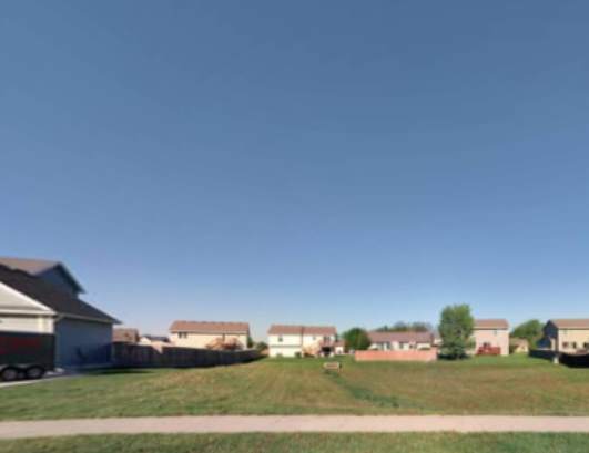 An image of a grassy area surrounded by houses.