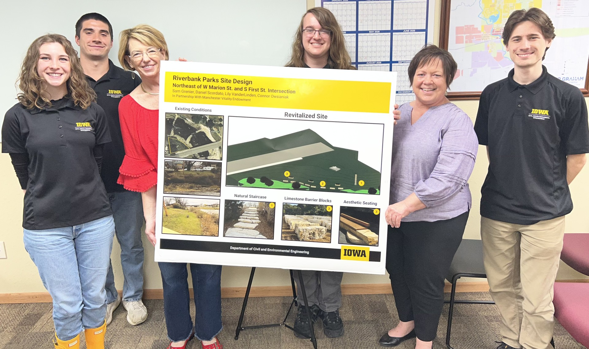 A group of students and community members stand smiling around a poster for a riverbank parks site design a poster 