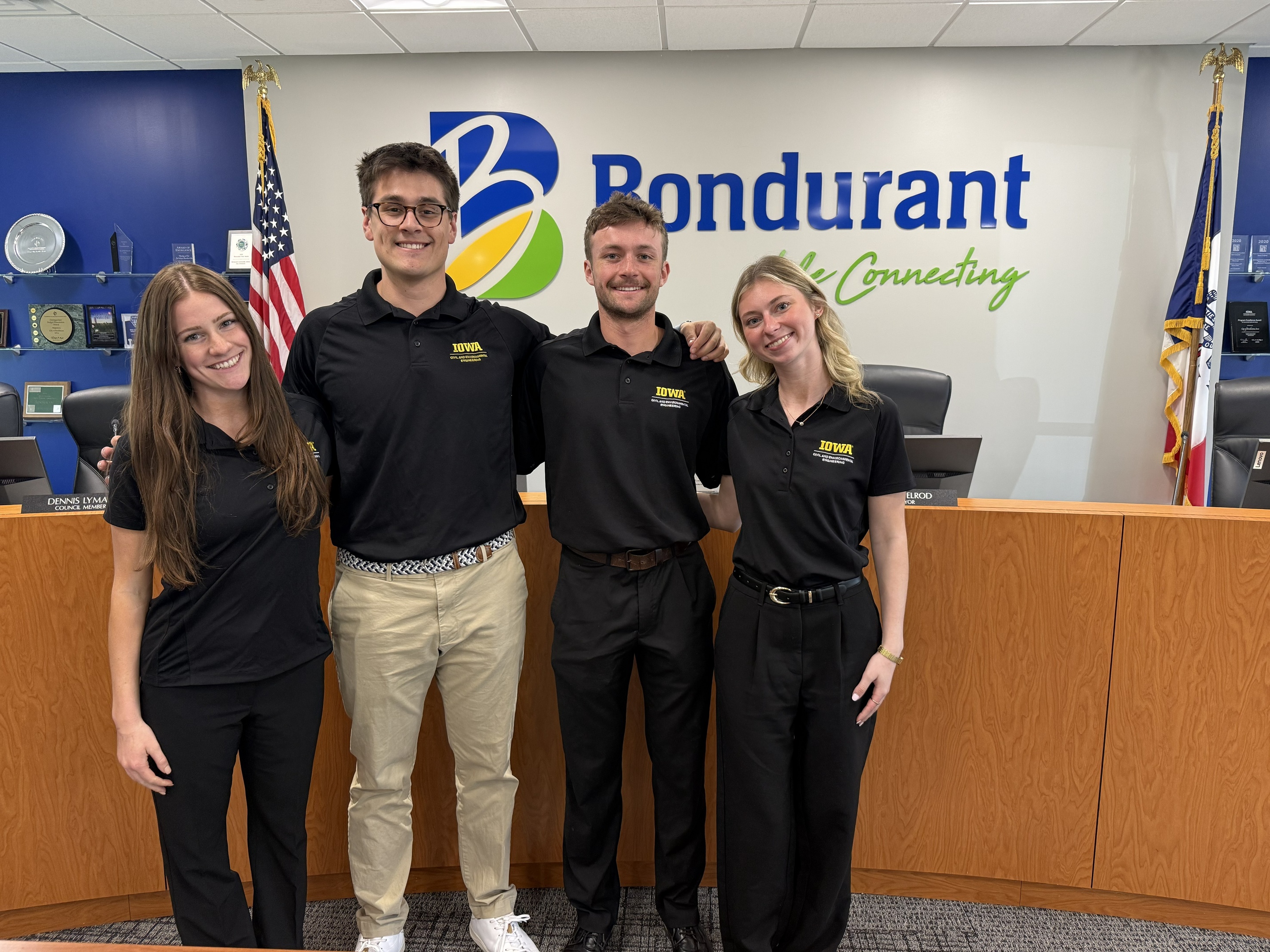 Four students wearing engineering polos stand in the Bondurant City Council Chambers
