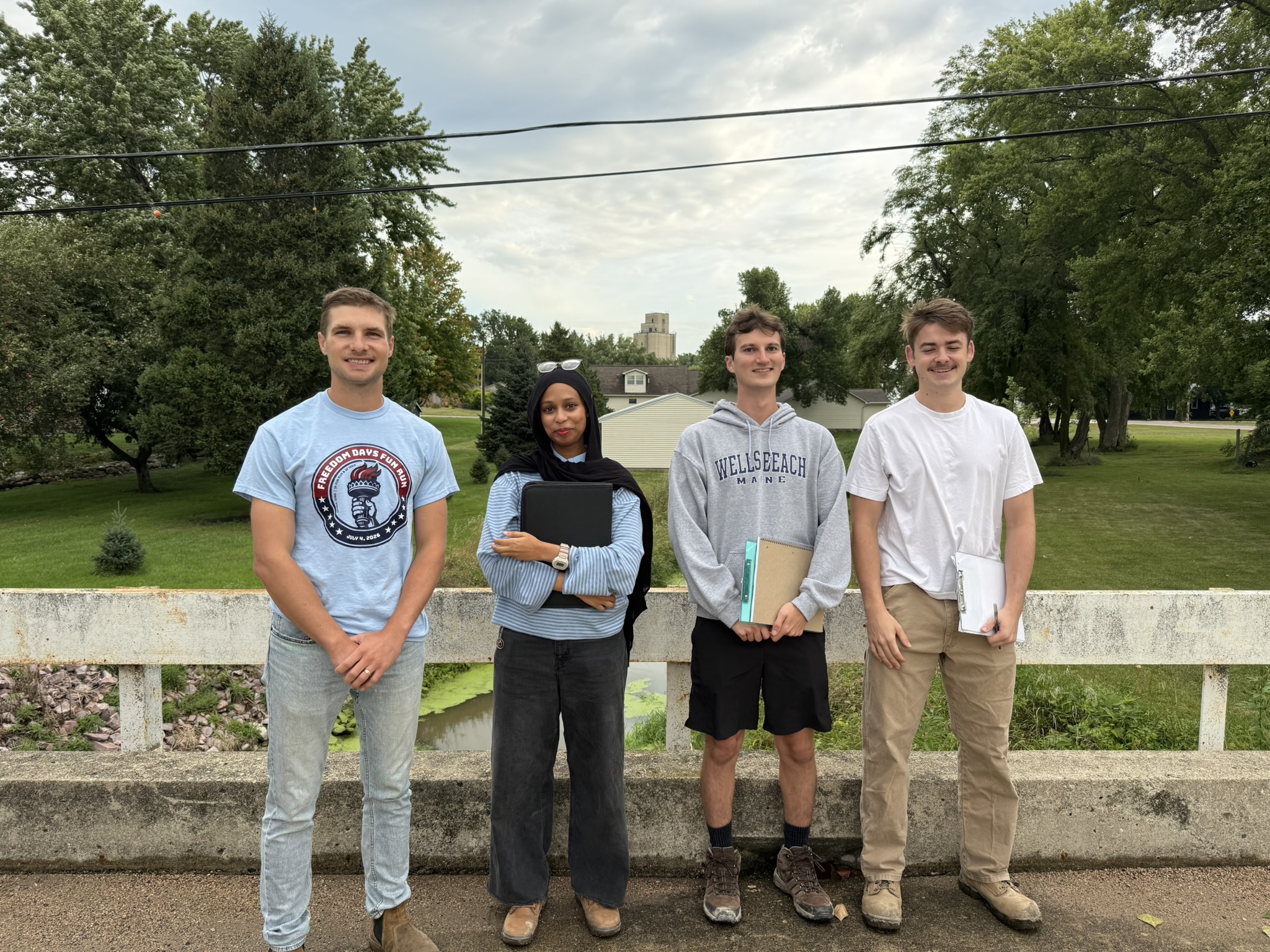 A group of four people stand on a bridge