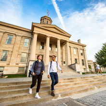 Two students on the steps of a traditional university building.