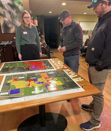 Three people look down at a table with a map of West Branch