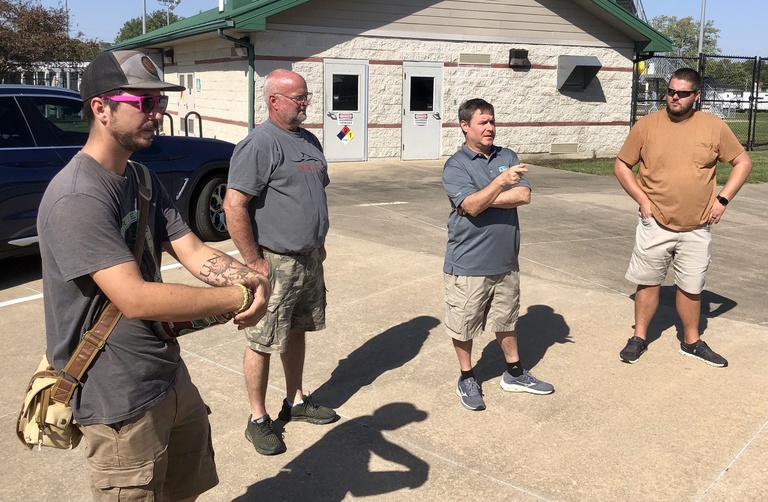 group of four men standing outside near a pickup truck