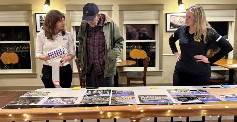 Three people look down at a table with photos of homes.