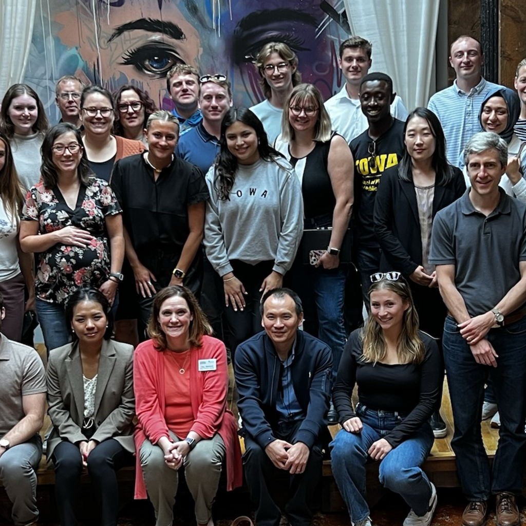 large group photo in front of colorful indoors mural