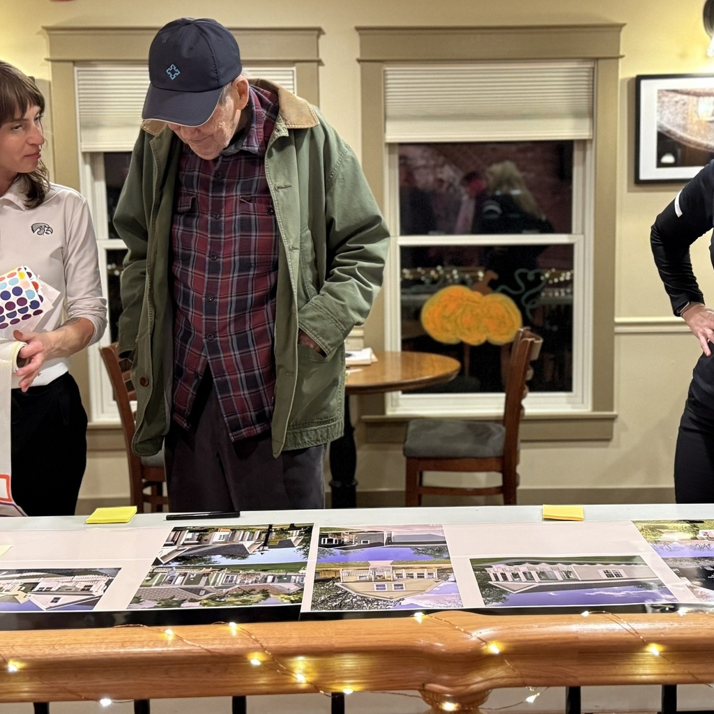 Three people look down at a table with photos of homes.