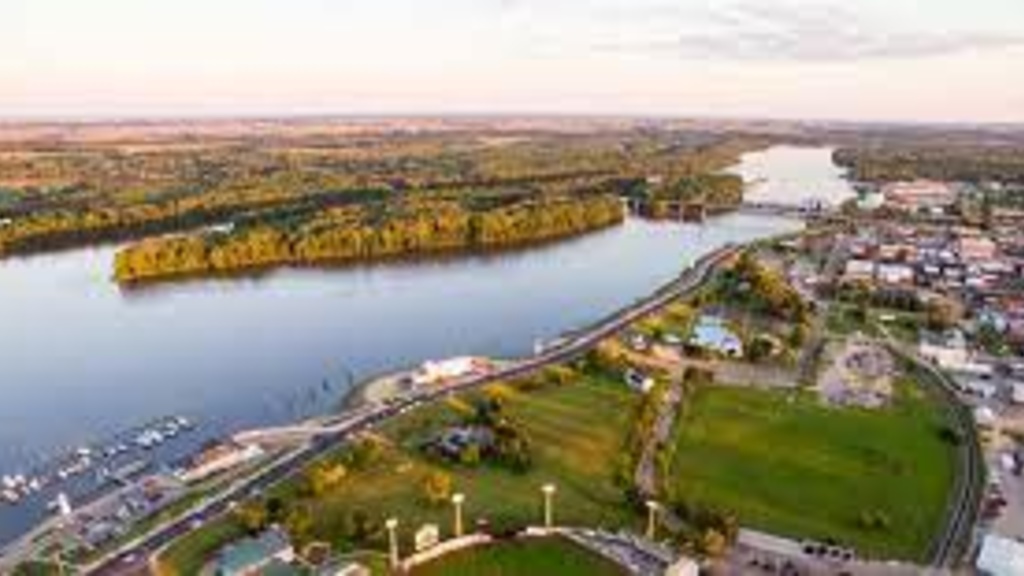 an image from the sky of a small town on a wide river at dusk.