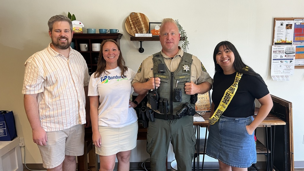 Group of four people smile at at the camera, one man is wearing law enforcement gear. 