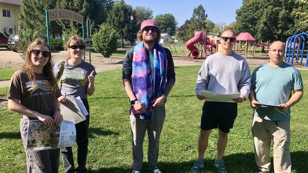 Group of five young people standing outside on a sunny day.