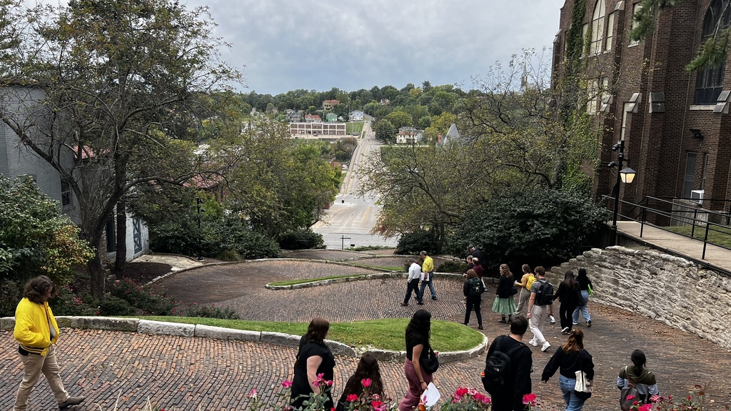 people walking down curvy brick street