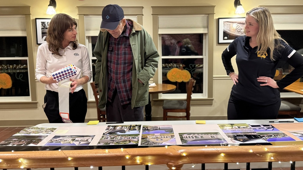 Three people look down at a table with photos of homes.