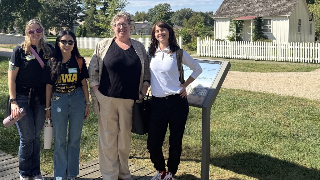 A group of 4 women stand in front of a the small white house that is Hoover's birthplace.