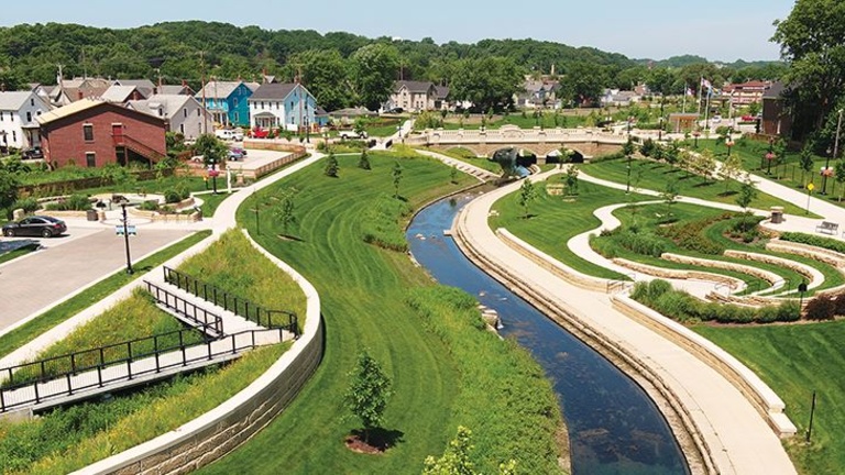 aerial of a creek with interesting, new curved walkways and limestone banks