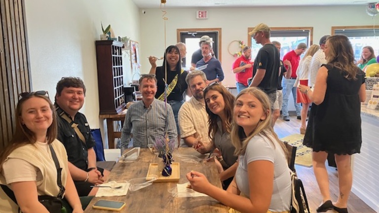 a group of young people sit at a table in a restaurant and smile for the camera.